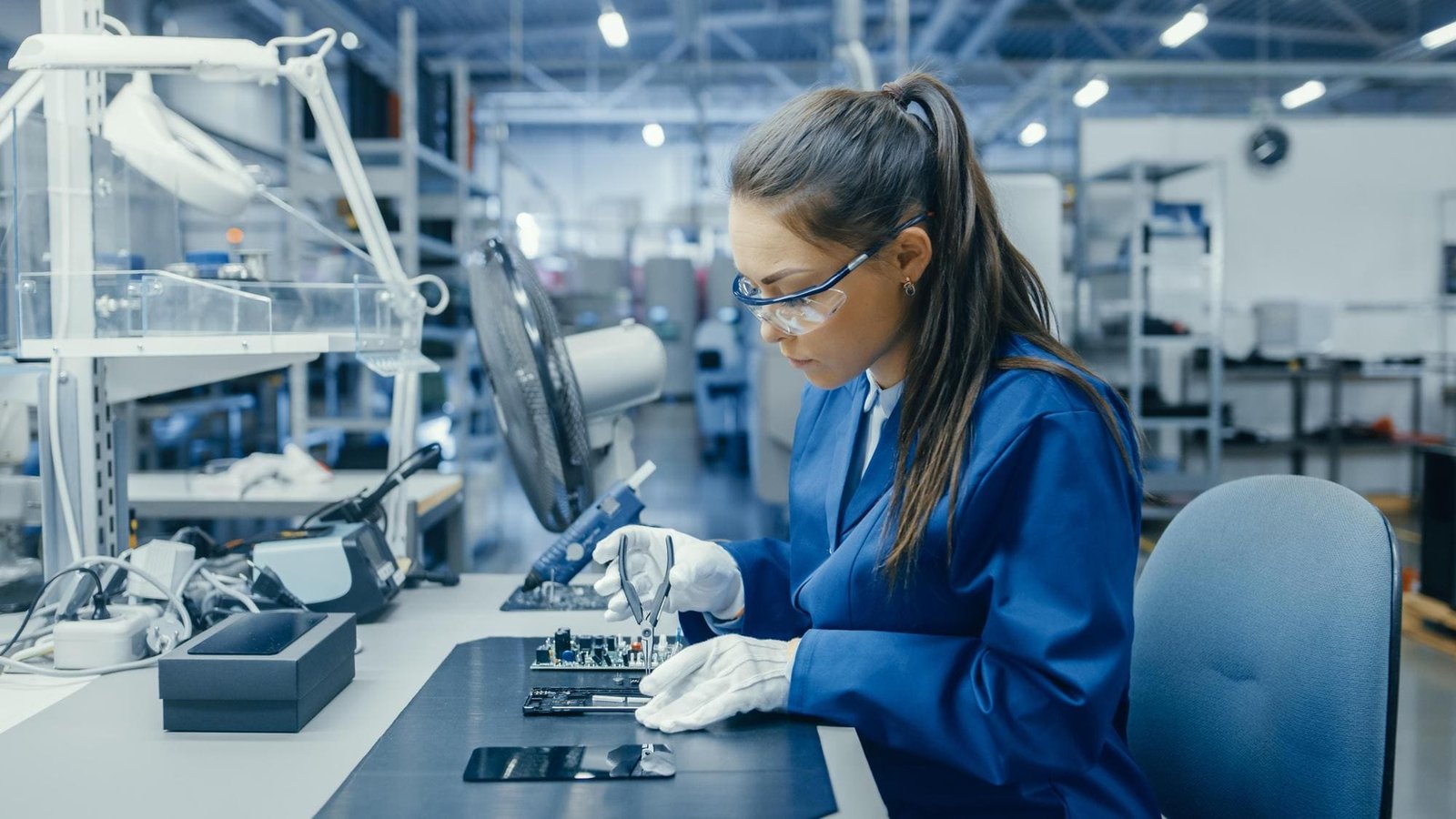 Technician in a lab coat assembling a circuit board.