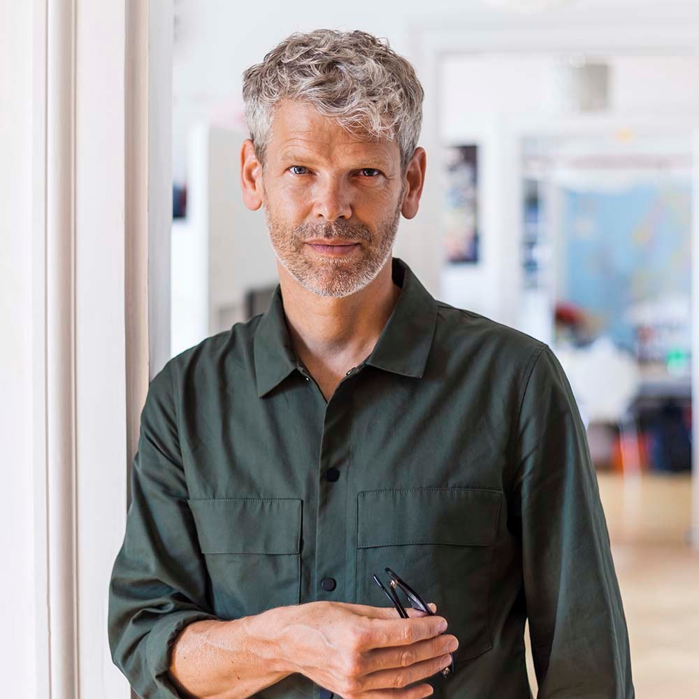 Man with gray hair holding glasses