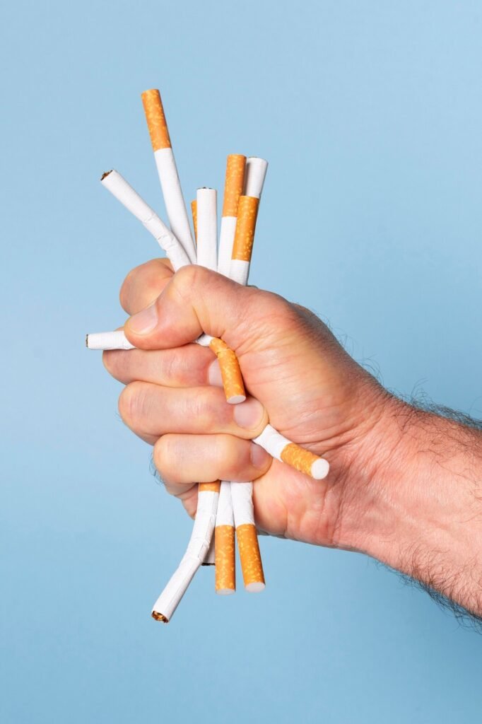 Hand crushing cigarettes against blue background
