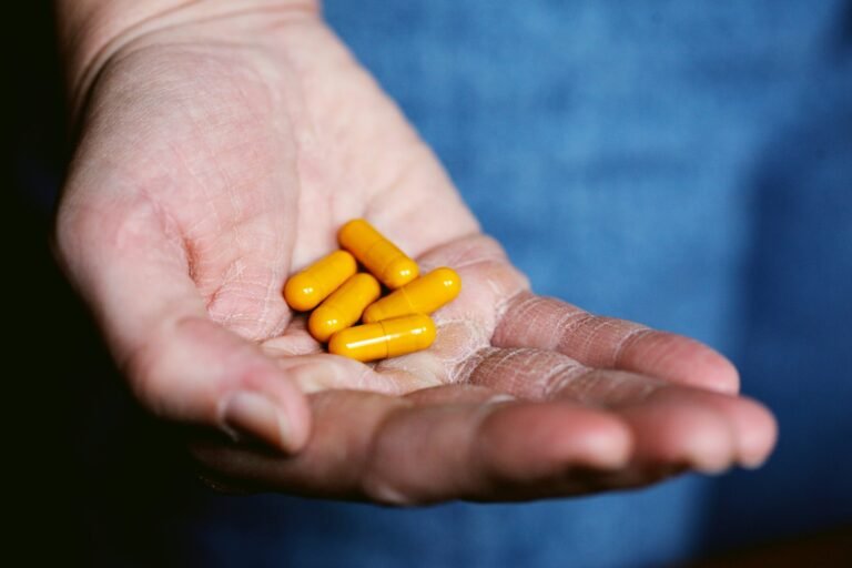 Hand holding yellow medicine capsules