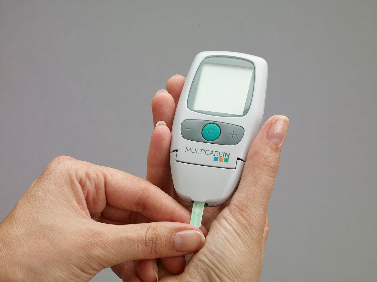 Hands inserting test strip into blood glucose meter