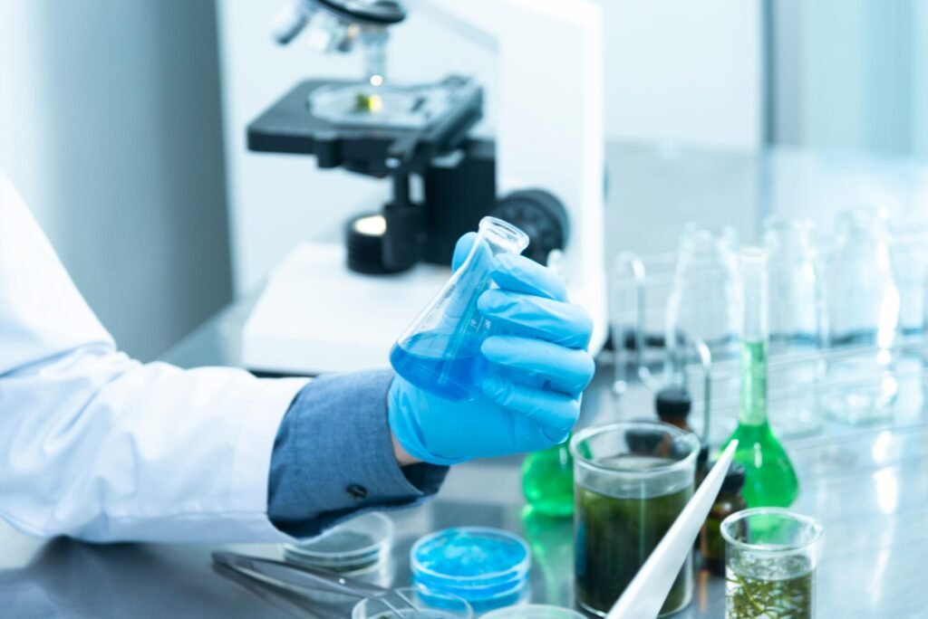 Gloved hand holding blue chemical flask in laboratory