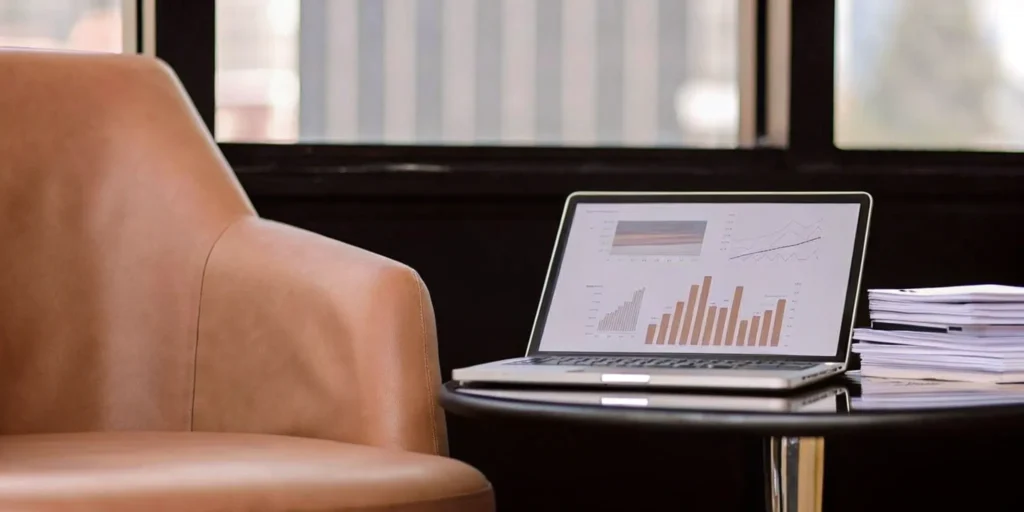 Laptop with charts beside chair and papers